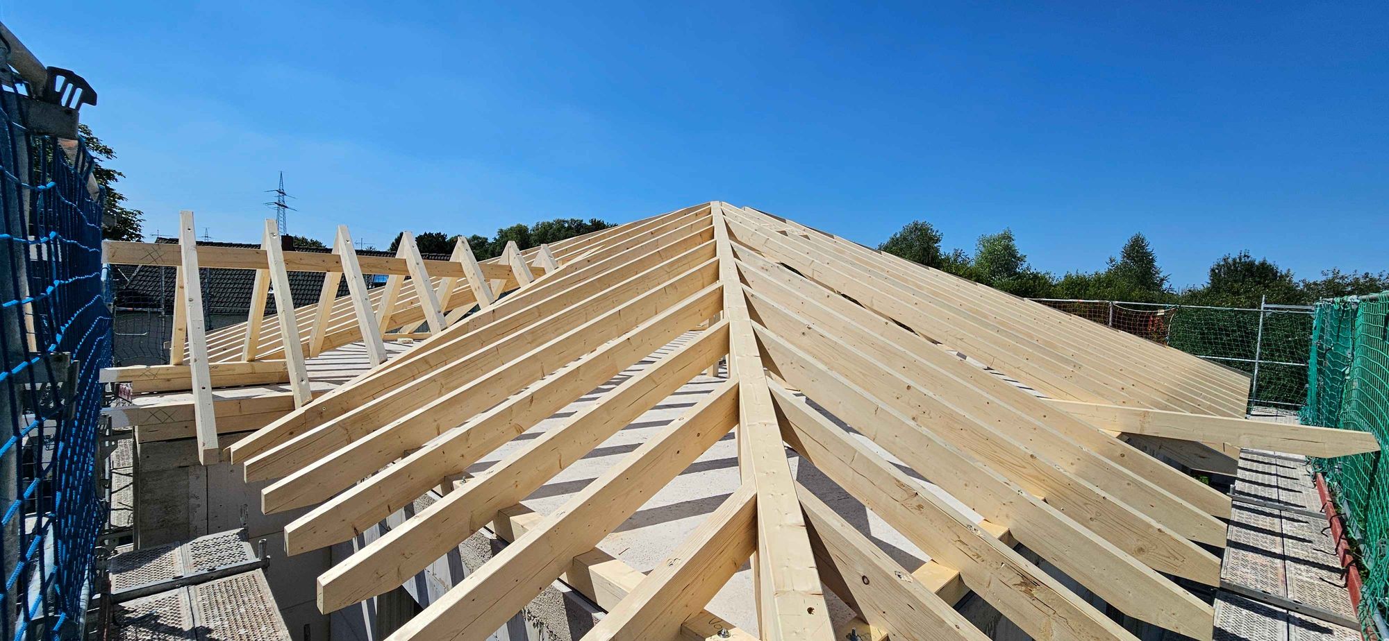 Neuer Dachstuhl aus Holz unter blauem Himmel