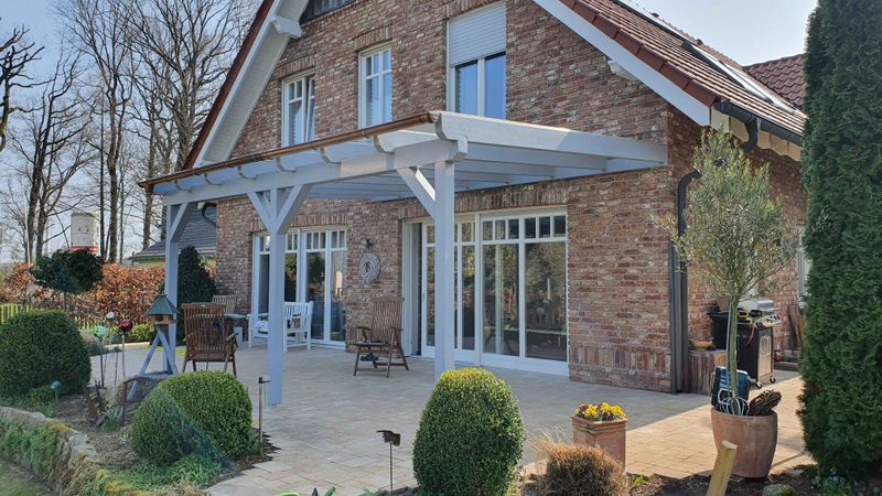 Weiße Terrassenüberdachung an einem Klinkerhaus
