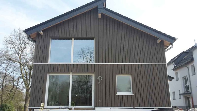 Wohnhaus mit dunkler, vertikaler Holzfassade