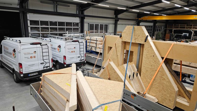 Firmenhalle mit Firmenfahrzeugen und vorbereiteten Holzbauteilen